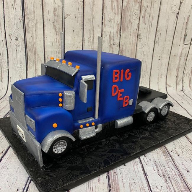 A carved birthday cake shaped like a blue semi truck