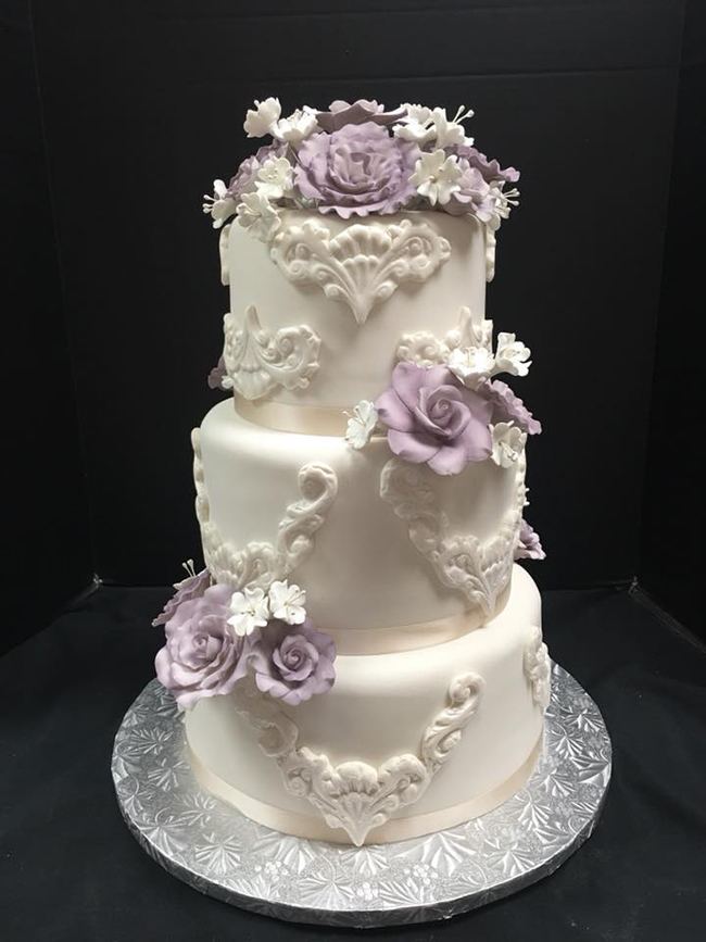 A three-tier ivory wedding cake with lavender sugar flowers