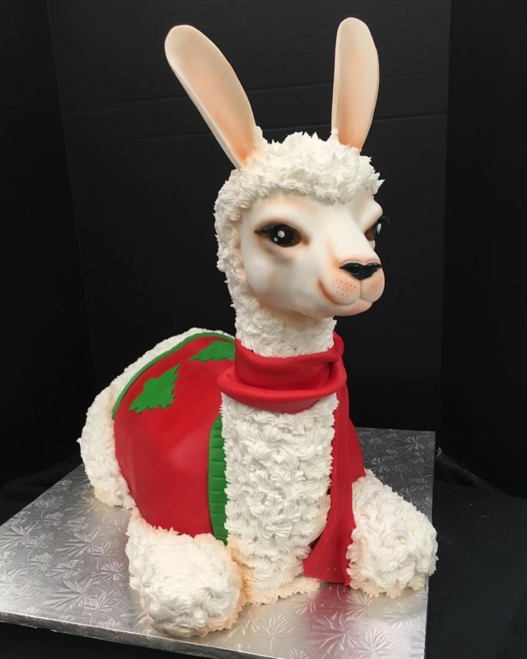 A sculpted llama cake with a red saddle blanket