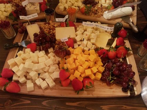 A charcuterie board with cheeses, berries and grapes