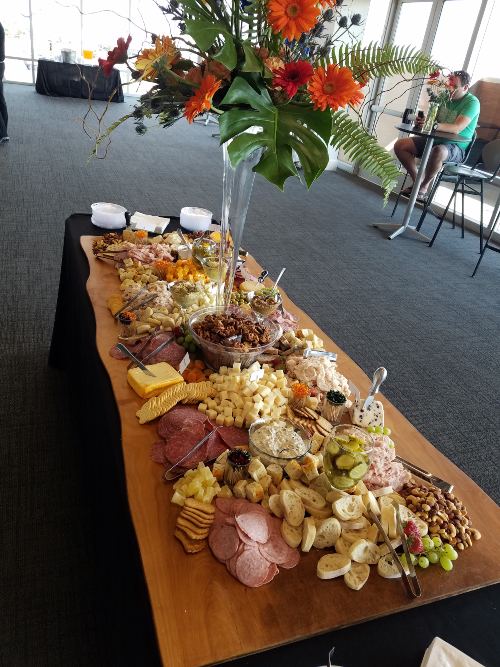 A long grazing table of cheeses, cured meats, fruit and crackers